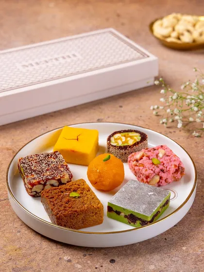 A close-up of various Indian sweets like ladoo, barfi, and peda from Meethi India. This shot highlights the variety and craftsmanship of the confections.