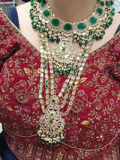 This is how a complete bridal set looks when worn. You can see the beautiful layering of the heavy choker and the long multi-layered haar, both featuring intricate work with green stones and kundan. This is the royal look every bride dreams of.