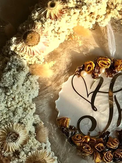 A close-up of the hanging logo wreath, showing the detail of the preserved flowers and the custom initial logo. It's a beautiful way to celebrate a new union.