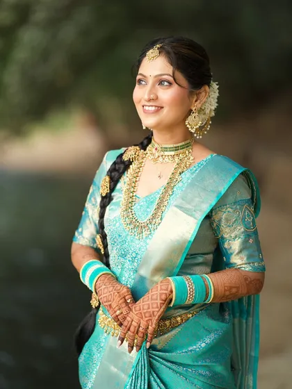 The bride looking radiant and happy. This shot showcases her complete look, from the traditional braided hairstyle to the layered temple necklaces.