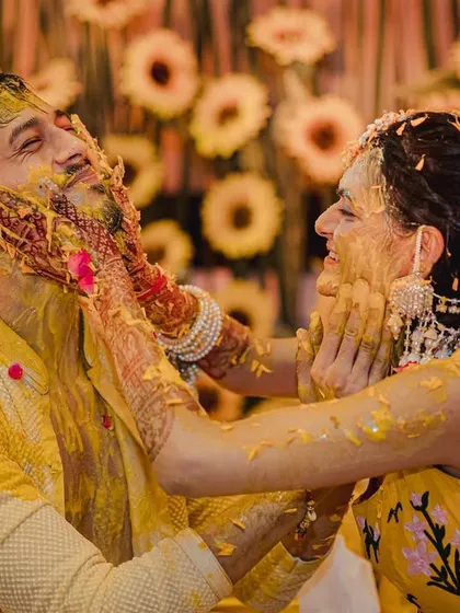 The playful side of a Haldi ceremony, where the couple lovingly smothers each other with turmeric paste against a backdrop of sunflowers. These are the fun, uninhibited moments that make a wedding memorable.