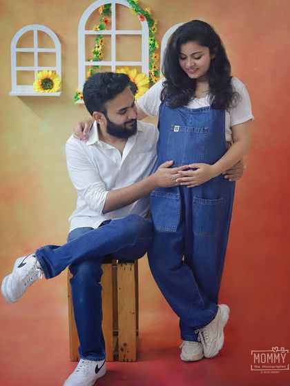 A sweet interaction between the parents-to-be. The casual denim outfits and the gentle touch on the belly make this a heartwarming and authentic maternity photo.