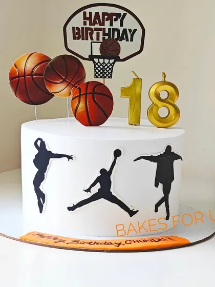 An 18th birthday cake for a basketball fan, decorated with player silhouettes, basketballs, and a hoop topper. It's a slam dunk for any sports-themed party.