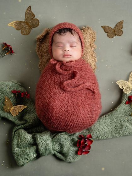 Like a butterfly emerging from a cocoon. This setup with a knitted wrap, bonnet, and delicate butterfly accents creates a whimsical and magical portrait.