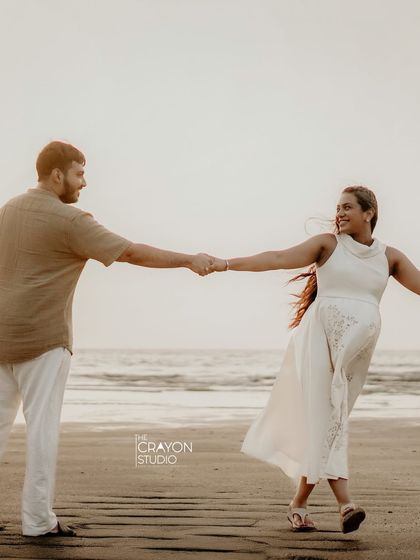 A joyful, carefree moment on the beach. Holding hands and spinning around, their happiness is infectious in this candid style pregnancy photo.