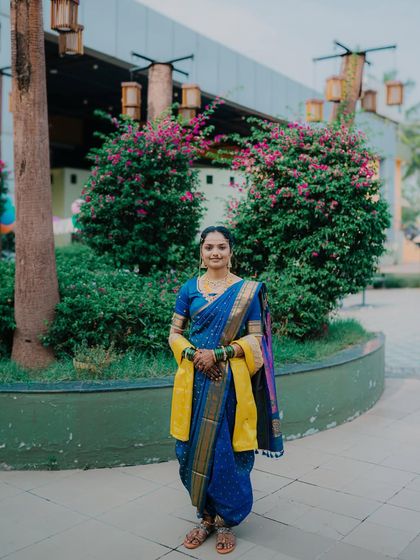 A full-length portrait of the bride, Sneha, in her stunning blue navari saree, standing confidently in a beautiful outdoor setting in Sambhaji Nagar.