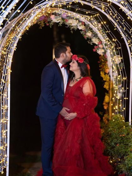 A romantic night shot under a floral archway lit with fairy lights. This couple shares a tender kiss, creating a magical and memorable outdoor portrait.
