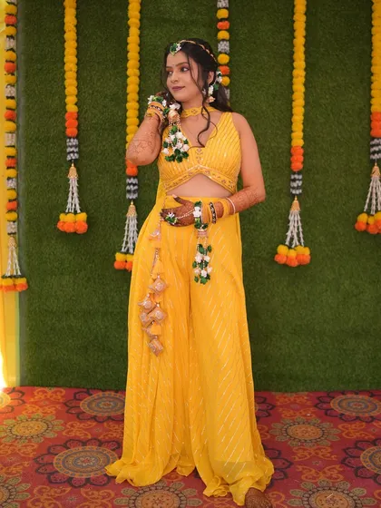 A full-length view of the bride's modern Haldi outfit. The simple, elegant hairstyle complements the vibrant and fun atmosphere of the event.