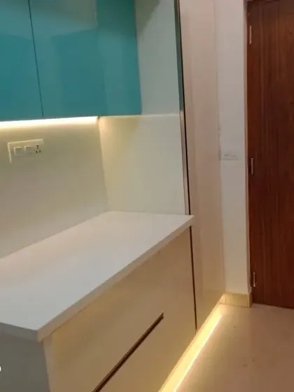 Here we showcase a dedicated counter space perfect for small appliances. The warm LED strip lighting under the high-gloss teal cabinets not only illuminates the work surface but also adds a touch of modern elegance to the kitchen's overall design.