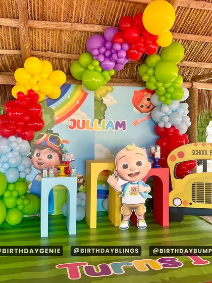 A Cocomelon "Turns One" party with a school bus cutout and a rainbow backdrop. The primary-colored balloons are perfect for this theme.