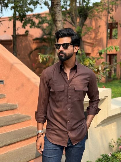 The rich brown color of the shirt is complemented by the natural surroundings, making it a great choice for a relaxed, stylish look.