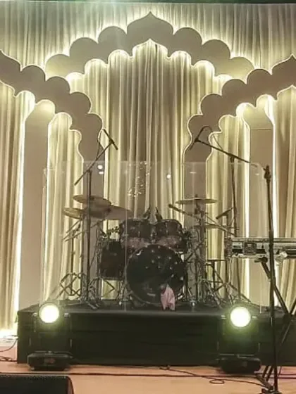 The stage for the evening's entertainment, featuring a backdrop of softly lit ivory drapes framed by an elegant scalloped archway. This design provided a sophisticated and visually stunning setting for the live band.