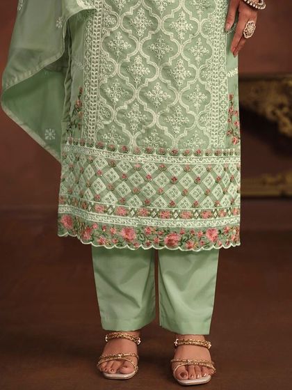 The delicate floral embroidery on the hem of this light green salwar kameez adds a touch of romance and femininity.