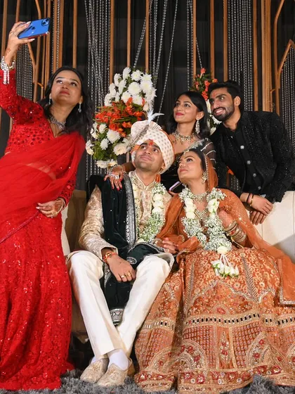 Another fun group selfie from the wedding stage. The variety of colors and styles, from a red sequin saree to a classic suit, is what makes wedding fashion so exciting.
