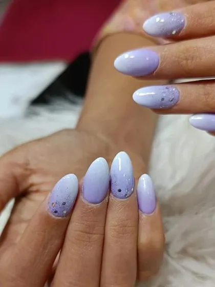 A still shot of the lavender and white ombre nails with scattered glitter, a soft and pretty design.