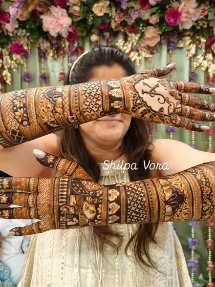 The bride crossing her arms to showcase the incredible detail and coverage of her wedding mehndi.