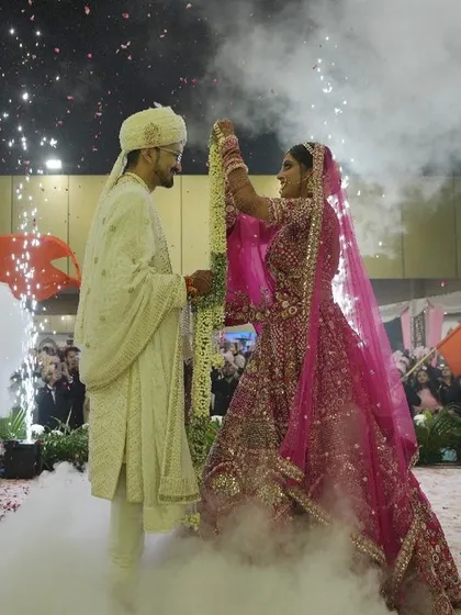 The bride places the garland on the groom during their Jaimala, surrounded by clouds of smoke and sparkling pyrotechnics. I design these moments to be filled with drama and beauty.