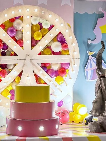 Another angle of the vibrant carnival cake stage. This view shows the scale of the lit Ferris wheel and the placement of the elephant prop, creating a balanced and visually appealing setup.