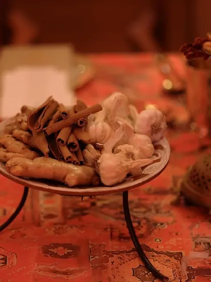 A simple yet evocative detail, with a plate of ginger and cinnamon sticks placed on a table with a traditional patterned cloth.