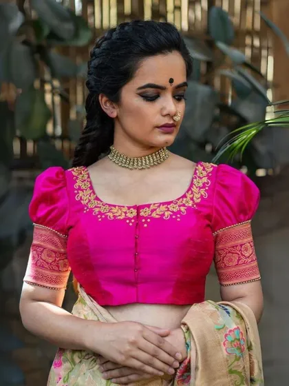 A full view of the hand-embroidered magenta blouse, paired with a saree. You can see how the custom fit and puff-sleeve design create a balanced and elegant silhouette, perfect for weddings and festive events.
