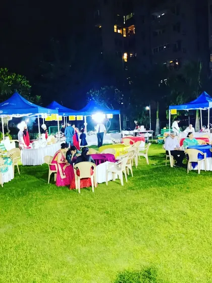 This image shows the seating and food stall area at a large outdoor festival. I arrange canopies for food counters and provide ample seating for guests to relax and eat.