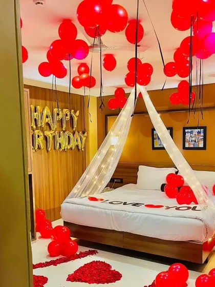 I can create a cozy and romantic birthday atmosphere right in your bedroom. This setup features a bed canopy with fairy lights, red balloons, and a path of rose petals, making it perfect for a couple's celebration.