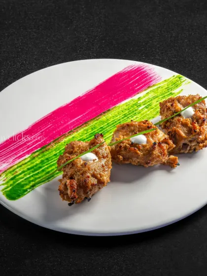 An artistic plating of chicken tikkas with colorful sauce smears, showcasing a modern approach to Indian appetizers.