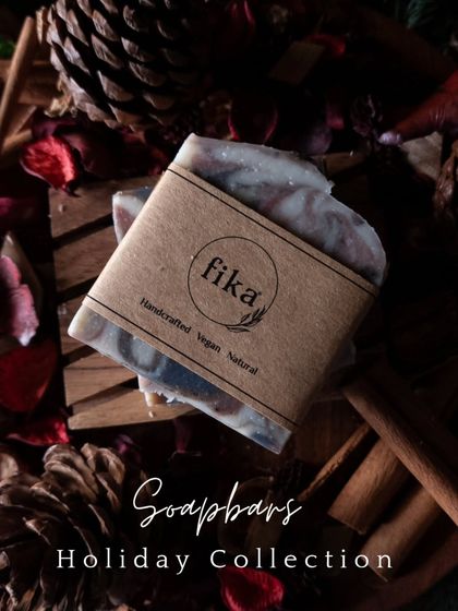 My 'Into the Woods' soap bar is a seasonal favorite, and this image captures its rustic charm. The soap, with its simple kraft paper label, is set against a backdrop of pinecones, cinnamon, and dried petals, evoking its warm, woodsy scent.