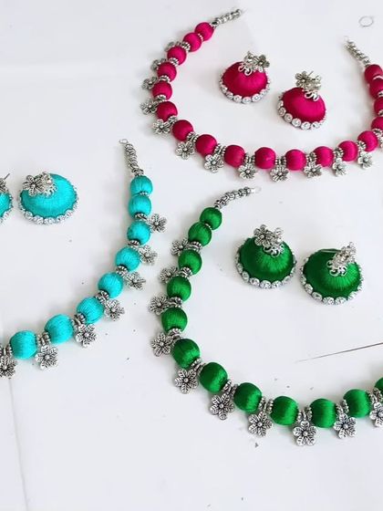 A closer look at the vibrant silk thread necklaces, each with matching jhumki earrings. These are perfect as return gifts or for adding a pop of color to your Navratri outfit.