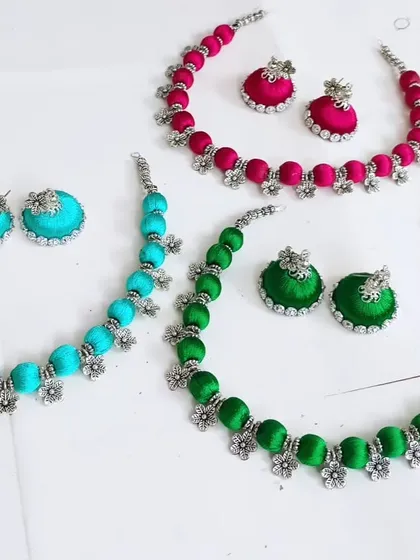 A closer look at the vibrant silk thread necklaces, each with matching jhumki earrings. These are perfect as return gifts or for adding a pop of color to your Navratri outfit.