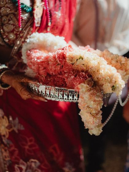 A close-up of the beautiful Varmaala garlands, made from delicate pink and white flowers and strung with pearls, resting on a silver platter before the ceremony.