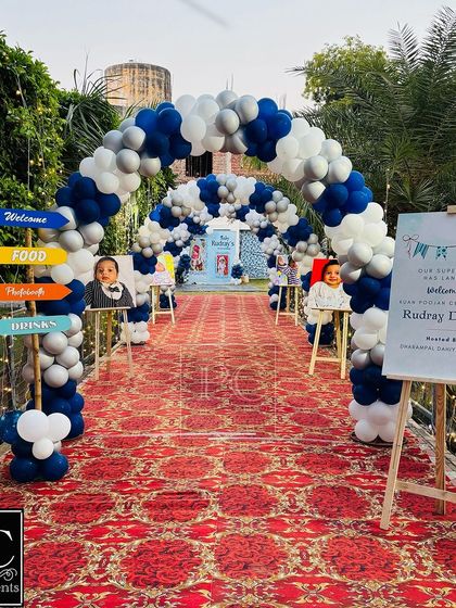 A grand entrance for Baby Rudray's Kuan Poojan ceremony. A long walkway is lined with blue, white, and silver balloon arches, leading guests to the main event area in style.
