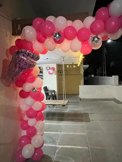 A simple balloon arch decoration for a home entrance or terrace. This pink and white arch, featuring an "It's a Girl" foil balloon, is a great way to announce the new arrival to guests and neighbors.