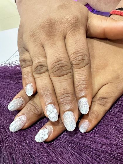 A full set of sparkling white glitter nails. The simple, sculpted 3D flowers on the accent nails add a touch of elegance and texture.