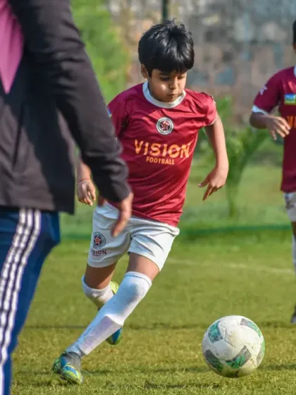 A player from our U10 team dribbles forward, with a coach observing from the sidelines. We provide constant guidance even during matches.