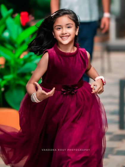 This young girl is running with a big smile, her beautiful dress flowing around her. This action shot perfectly captures the carefree joy of childhood during an outdoor birthday shoot.