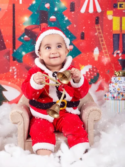 This little Santa is holding his jingle bells, looking up with a sweet, happy expression.