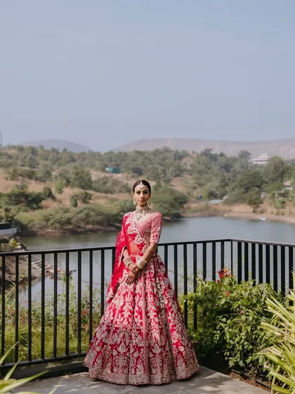 A full-length view of a stunning destination wedding look. The bride's vibrant pink lehenga stands out against the scenic backdrop, showing how my makeup and styling come together for a picture-perfect result, no matter the location.