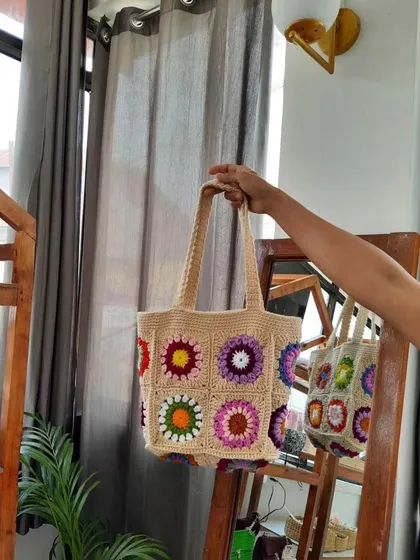 Here is a clear view of my multi-color granny square tote bag. The design features nine distinct squares, each with a different vibrant color combination, all stitched together with a light, neutral yarn that makes the colors pop.