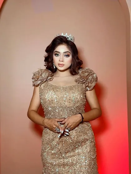 A close-up of a model wearing a golden sequined gown with a tiara. This look is perfect for a bride who wants to feel like a princess at her reception.