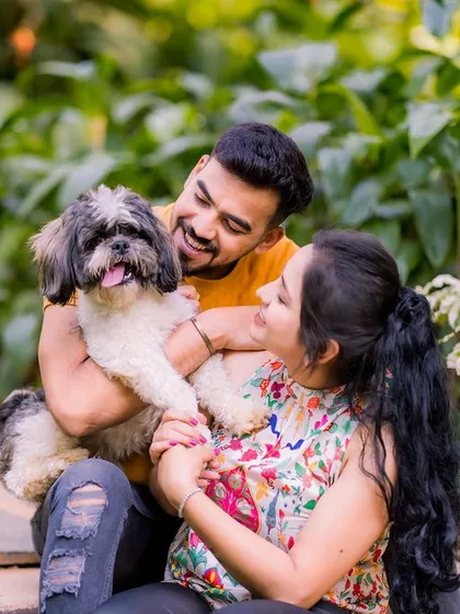 A happy couple plays with their dog on a garden staircase, a perfect way to include a furry friend in your shoot.