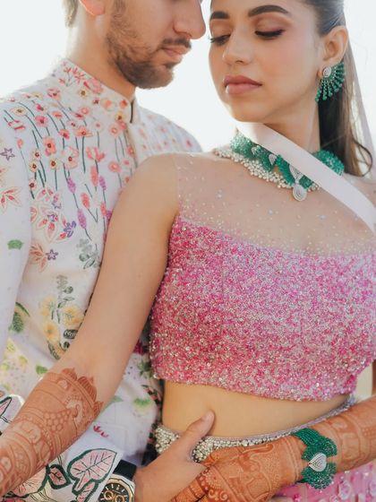 A close-up that highlights the vibrant colors and textures of the couple's outfits and the bride's henna. Their gentle embrace creates a tender and beautiful portrait.