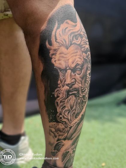 A dramatic, high-contrast shot of the Poseidon leg tattoo.