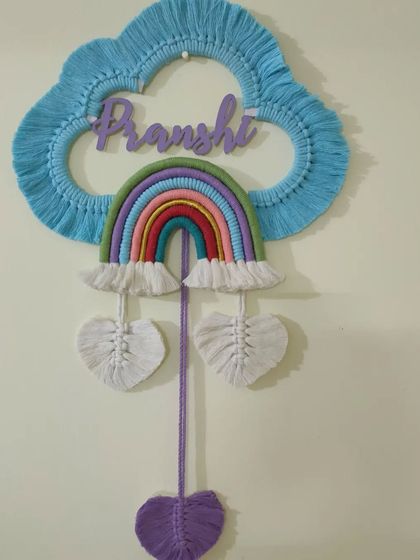 Another view of the custom macrame nameplate, showing the rainbow and cloud design.
