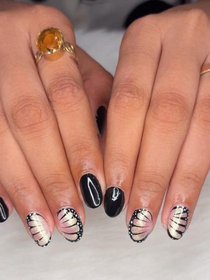 A stunning design featuring solid black nails paired with accent nails showing delicate, shimmering butterfly wings.