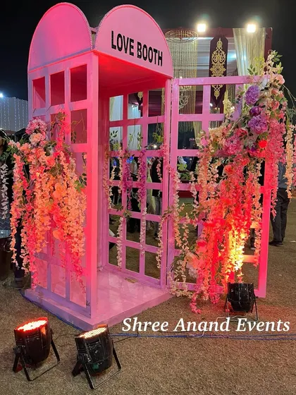 A fun and modern "Love Booth," designed like a classic pink telephone booth and adorned with cascading flowers, creating a perfect spot for photos.