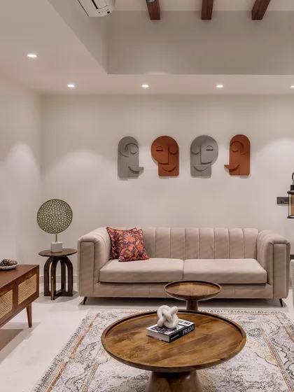 This family lounge in 'Project Lily' features a comfortable beige sofa, artistic face sculptures on the wall, and warm wooden furniture, creating a cozy and personal atmosphere.