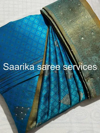 A teal blue saree with silver butis, folded and ready for a customer.