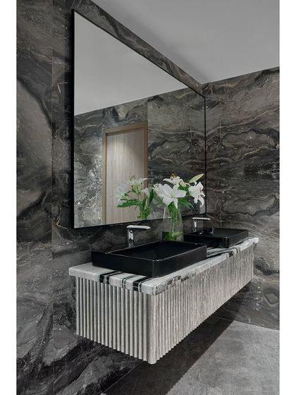 A custom-designed washroom vanity at the Blue Sea Banquet. The design features a fluted counter base and dramatic, book-matched marble walls, adding a touch of bespoke luxury to the common facilities.
