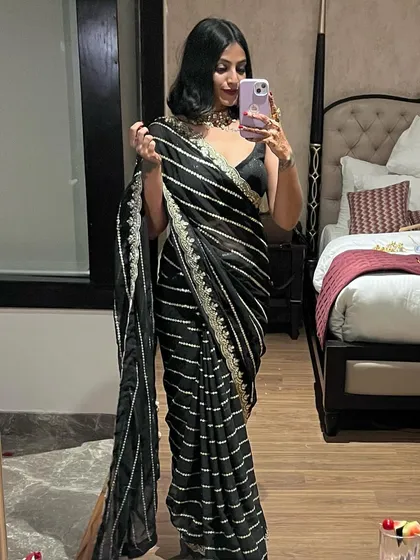 A full-length mirror selfie showing how the striped black saree drapes. It's a timeless piece that works beautifully for an evening wedding reception.